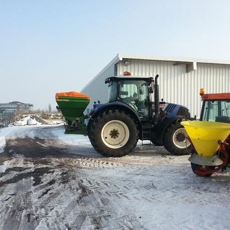 Zwei Traktoren stehen nebeneinander im Schnee, umgeben von einer winterlichen Landschaft