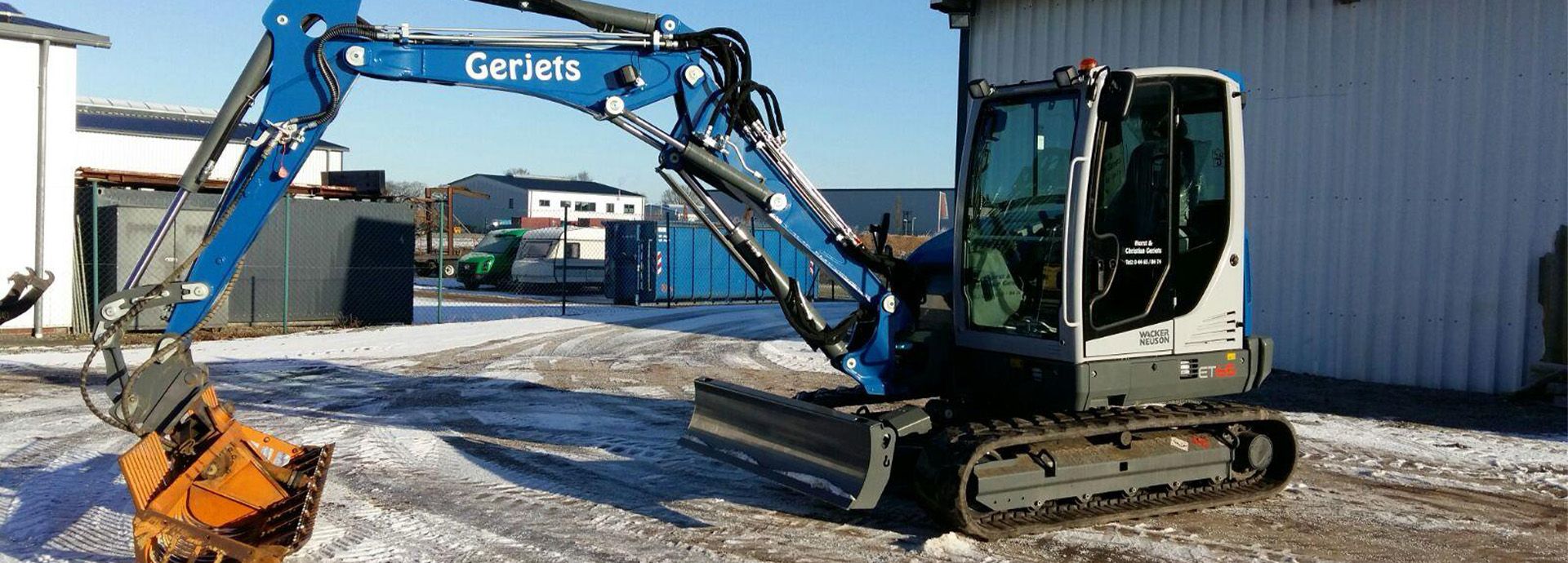Ein blauschwarzer Bagger ruht im Schnee, umgeben von einer ruhigen, verschneiten Umgebung